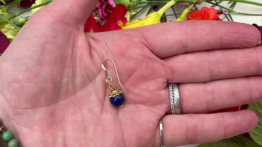 Lapis earrings on table with flowers. 