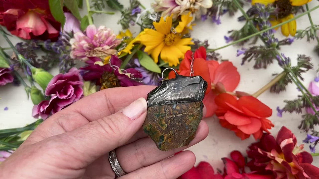 Petrified Wood pendant on table with flowers.