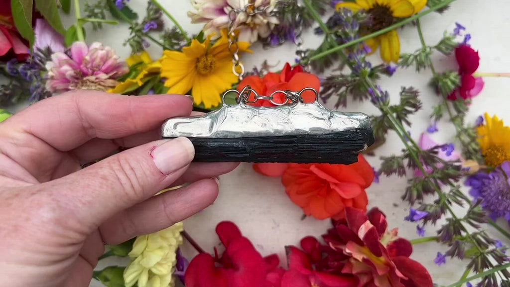 Black Tourmaline pendant on table with flowers. 