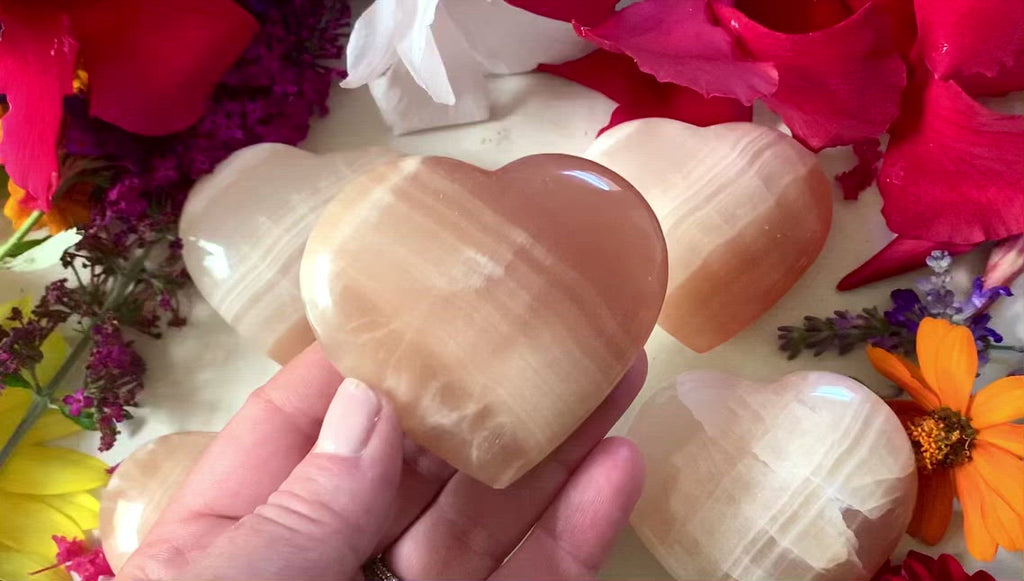 blood orange calcite heart with white swirls being shown on all sides. 