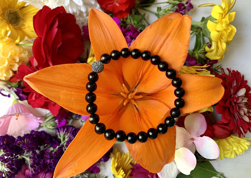 dark black jet bracelet sitting on bright orange flower.