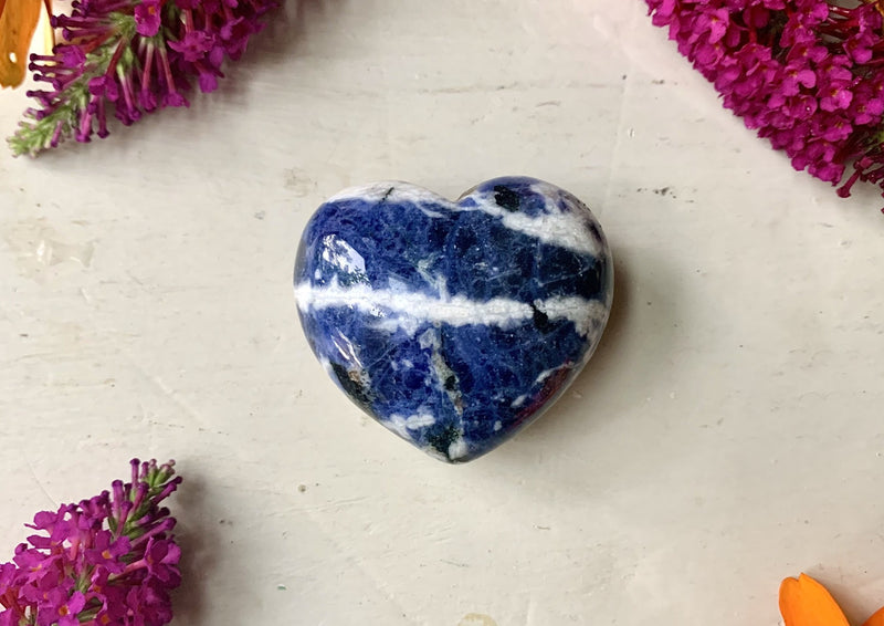 small sodalite heart blue with white and black veins running through it on tabletop.