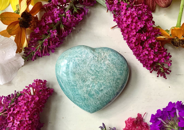One green crystal heart about 2 inches big on table with flowers