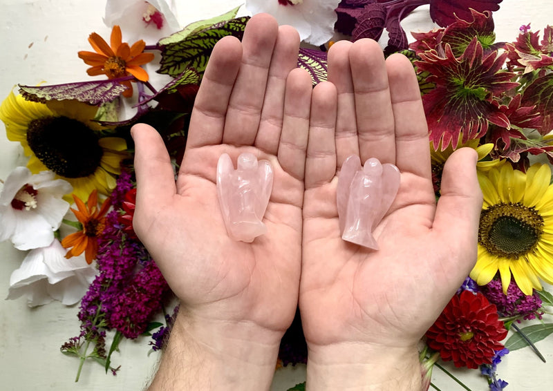 two male hands holding pink rose quartz small agels.
