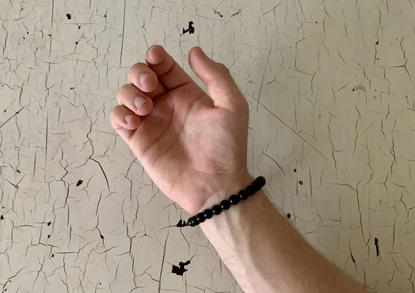 one male arm with dark black jet crystal energy bracelet