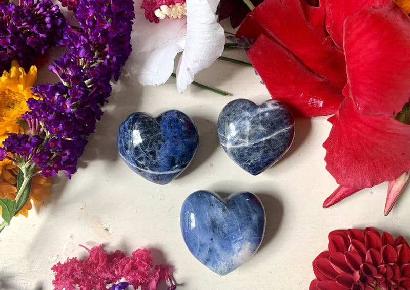 small sodalite heart blue with white and black veins running through it on tabletop.