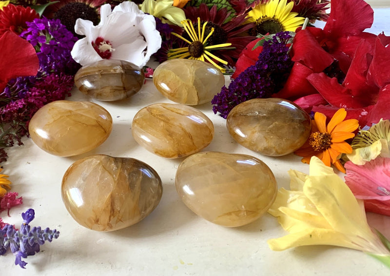 several golden yellow golden healer crystal hearts on a tabletop