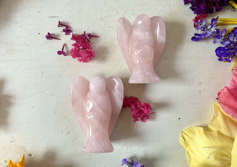 two pink rose quartz angels about 2 inches laying on tabletop.