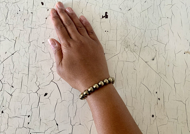 large golden pyrite crystal beads on female wrist.