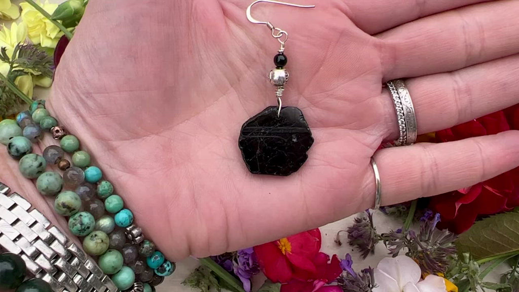 Black  Tourmaline earrings on table with flowers.