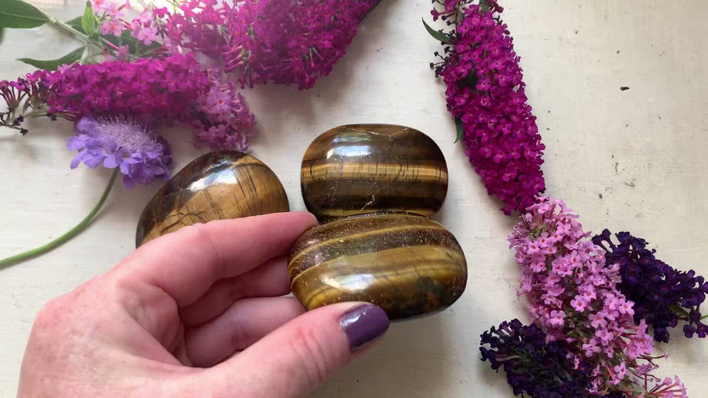 a video showing a brown and golden tigers eye palm stone