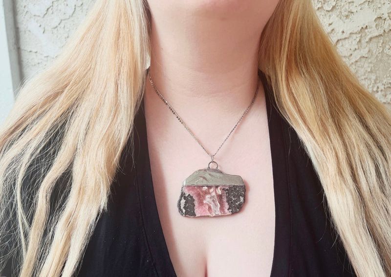 large rhodonite slab pendent soldered on sterling silver chain hanging around model's neck. 