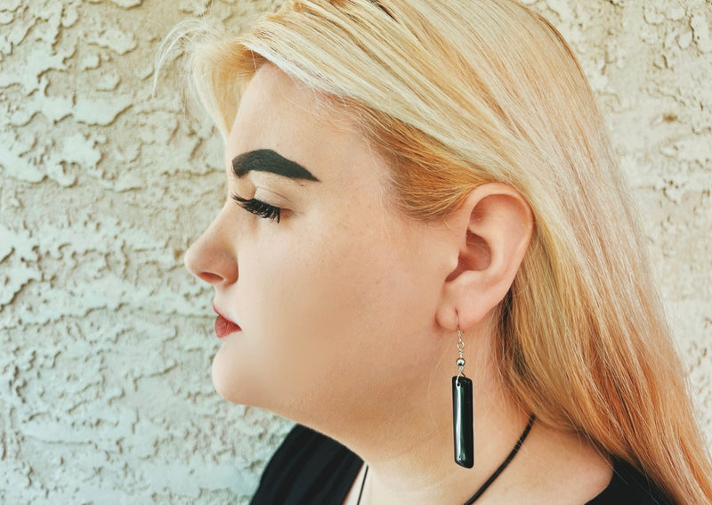black obsidian rectangular dangle earrings hanging on model's ear. 