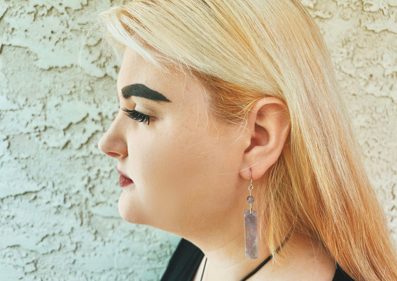Rectangular Amethyst earrings hanging from model's ear. 