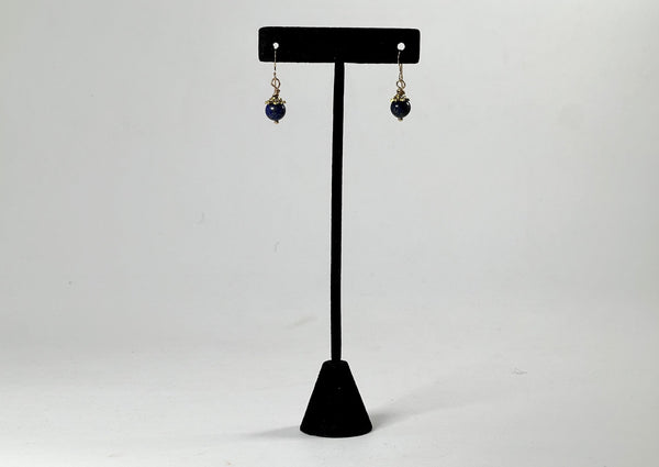 Large blue lapis drop earrings hanging from black t stand. 