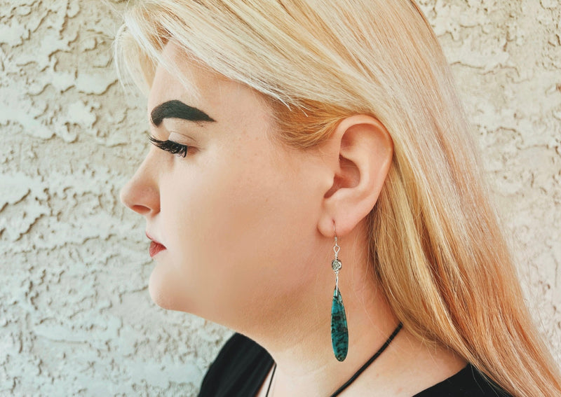 African Turquoise dangle earrings on silver hanging from model's ear. 