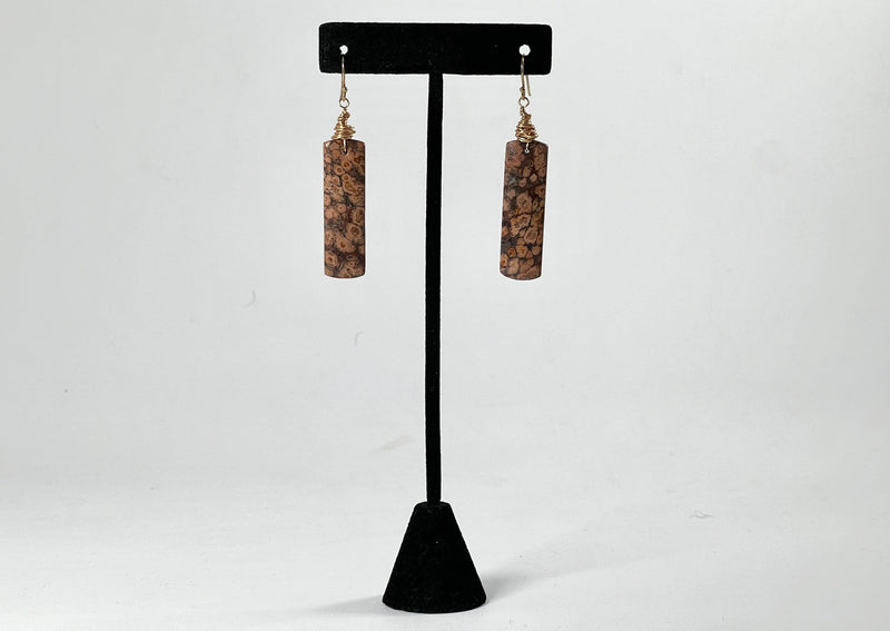 Red Orbicular Jasper rectangular earrings wrapped in 14GF hanging on black T stand. 