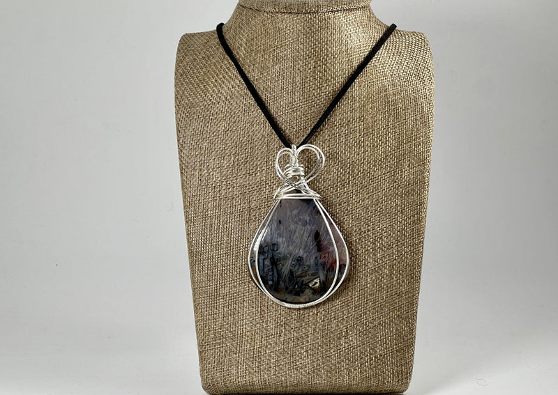 large agate pendant wrapped in silver on linen bust display