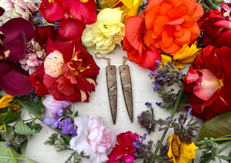 Red Creek Jasper Dagger earrings on table with flowers. 
