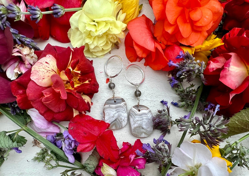 Crazy Lace Agate earrings on table with flowers.