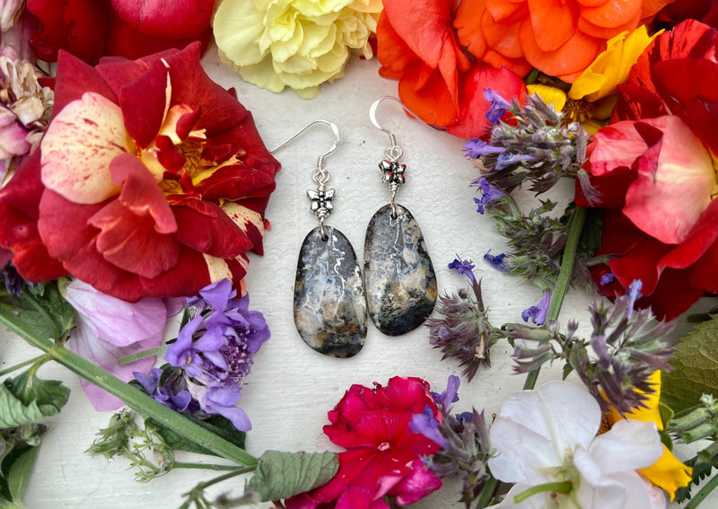 Dendritic Agate earrings on table with flowers.
