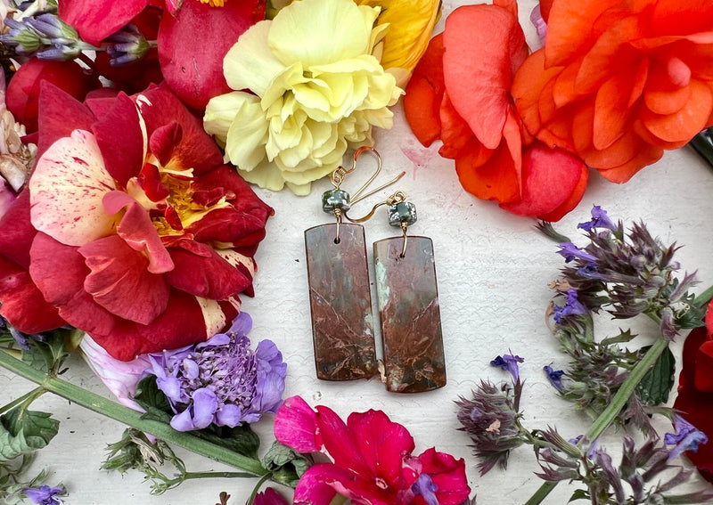 African Green Opal rectangular earrings on table with flowers. 