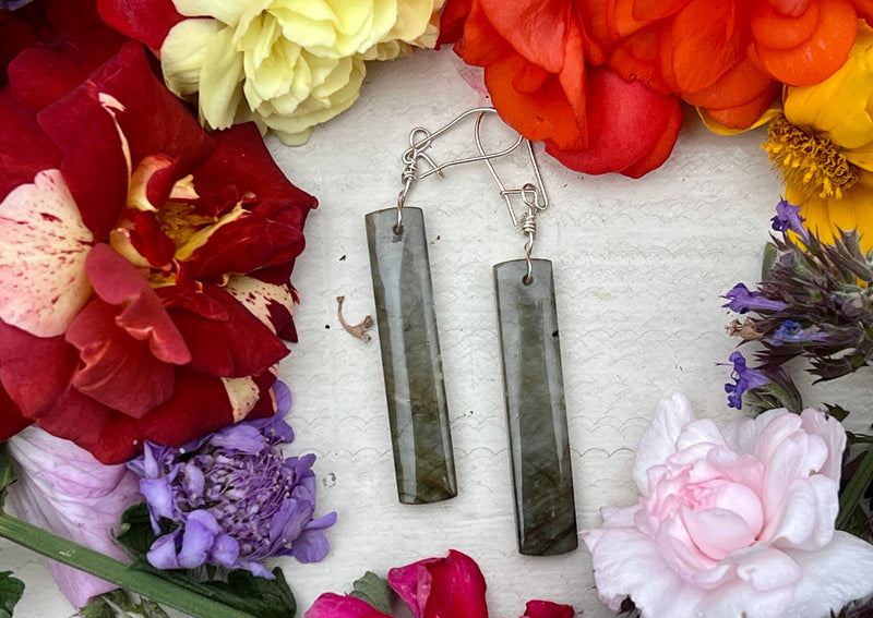 Labradorite earrings on table with flowers. 