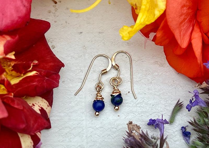 Lapis earrings on table with flowers. 