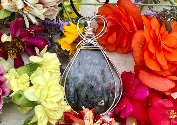 Large Agate on suede cord on table with flowers. 