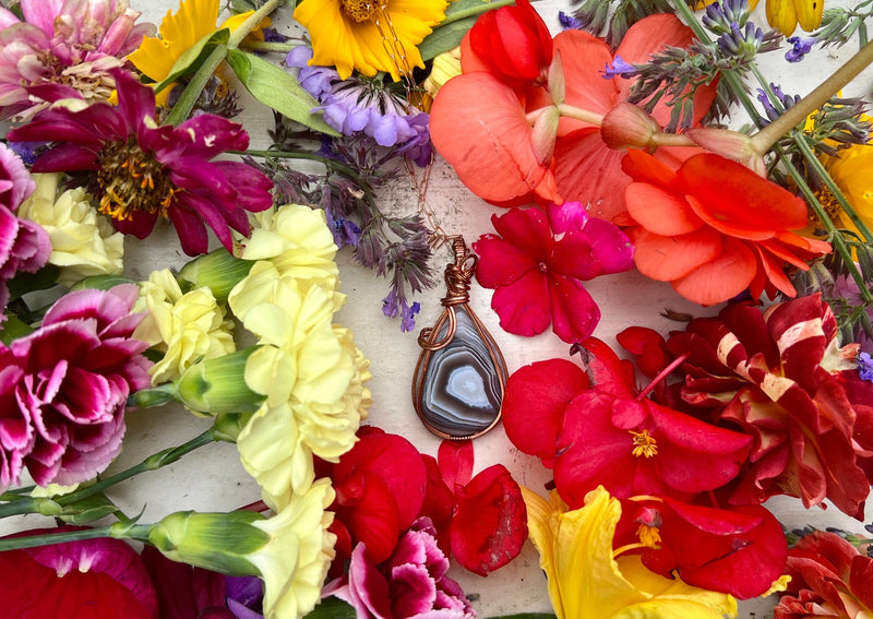 Large Botswana Agate pendant on table with flowers.
