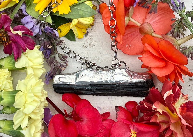 Black Tourmaline pendant on table with flowers. 