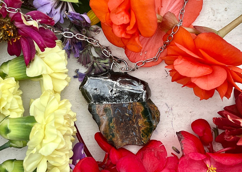 Petrified Wood pendant on table with flowers.